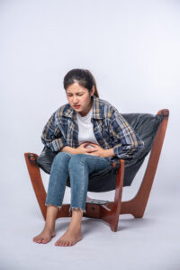 woman-sitting-chair-with-abdominal-pain-pressing-her-hand-her-stomach_1150-26005